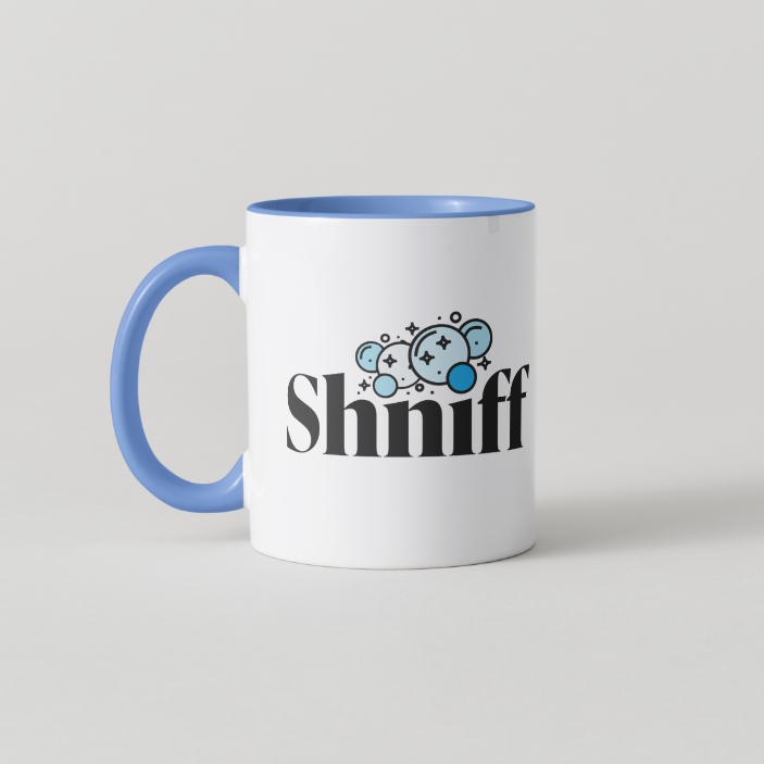 A white ceramic coffee mug with a blue handle and blue interior, featuring the word 'Shniff' in black stylized text with a blue cartoon sniffer graphic above it, on a light gray background.
